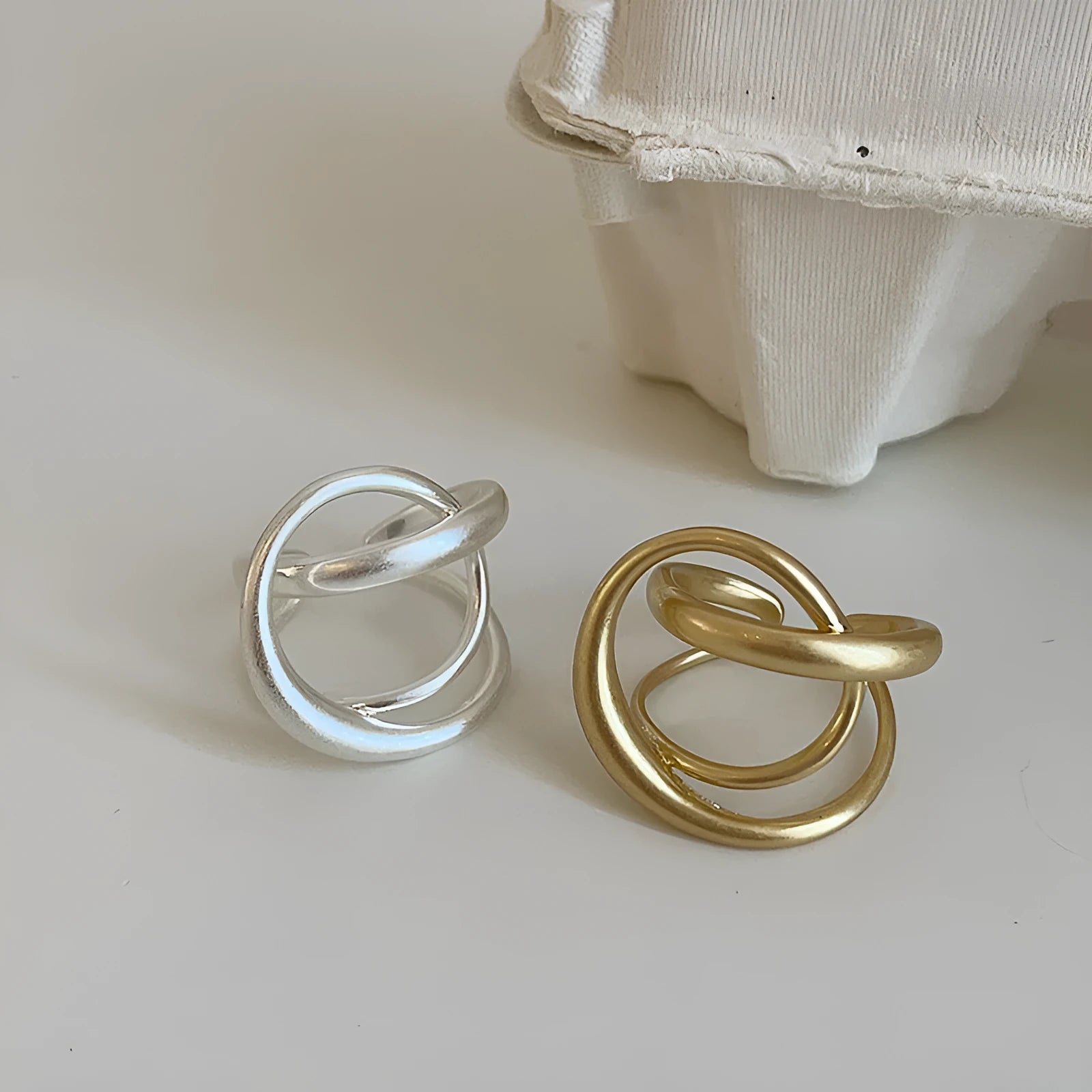 Geometric open ring for women with 3D interlaced matte metal design in gold or silver.