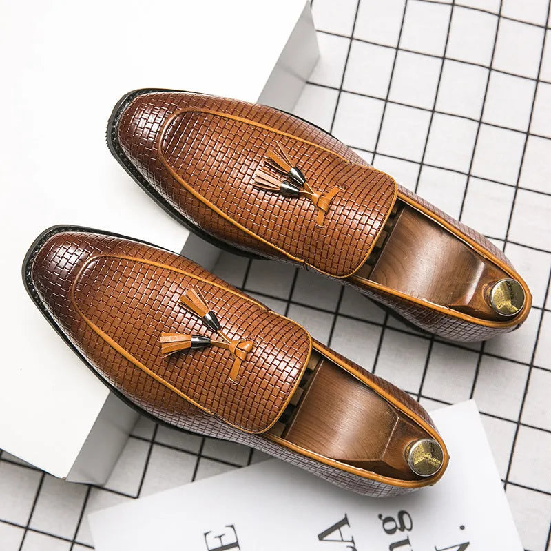 Men's black pointed toe slip on loafers with a tassel detail on the front, shown on a plain background.