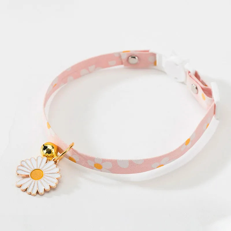Green adjustable pet collar with a metal bell and a pink bow tie attached, shown on a small dog.