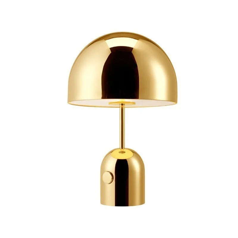 Mushroom shaped metal table lamp in rose gold finish on a wooden surface.