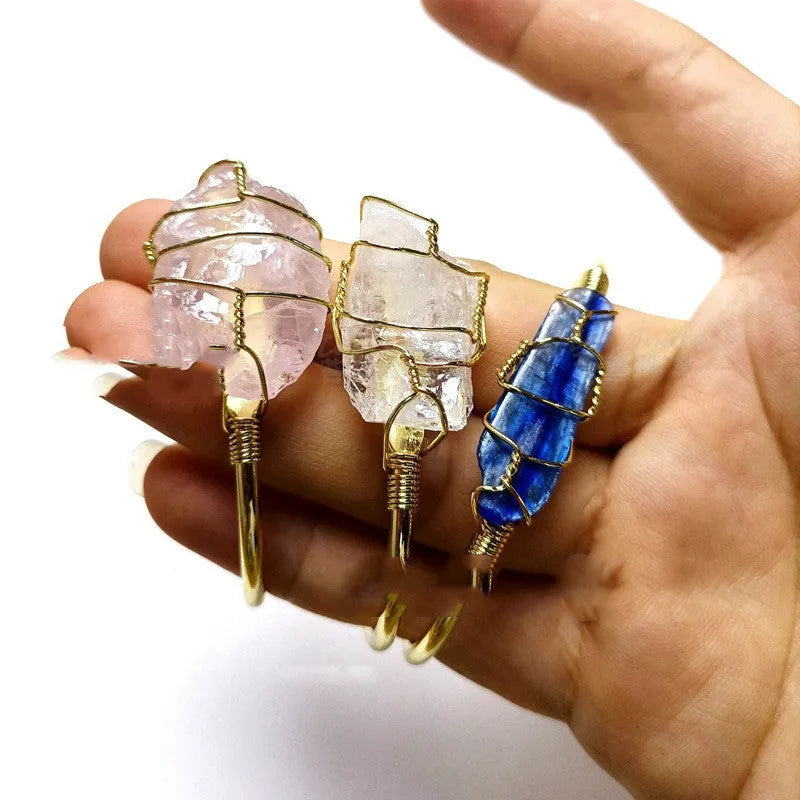 Gold winding geometric bracelet with unshaped rough natural crystal stones on a wrist.