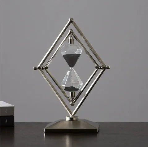 Glass sand clock with metal base showing coloured sand, in bronze or silver finish options.