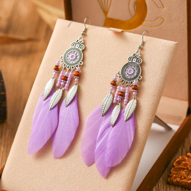 A pair of round drop leaf-shaped feather earrings in a chosen colour, showing Bohemian pattern details.