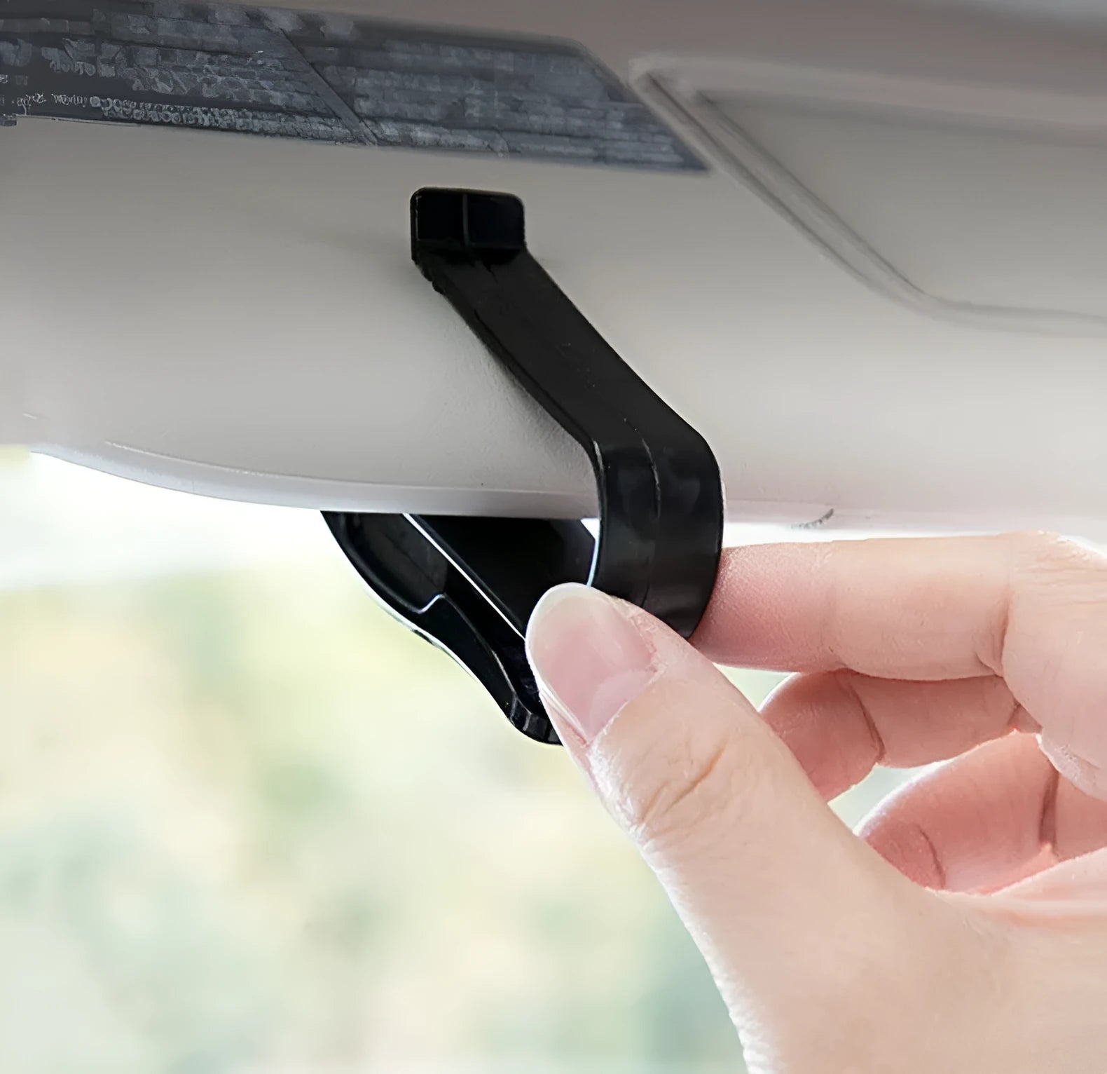Black plastic clip for holding glasses and cards on a car sun visor.