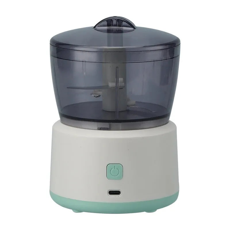 White mini electric meat grinder with transparent cup and stainless steel blade on kitchen counter