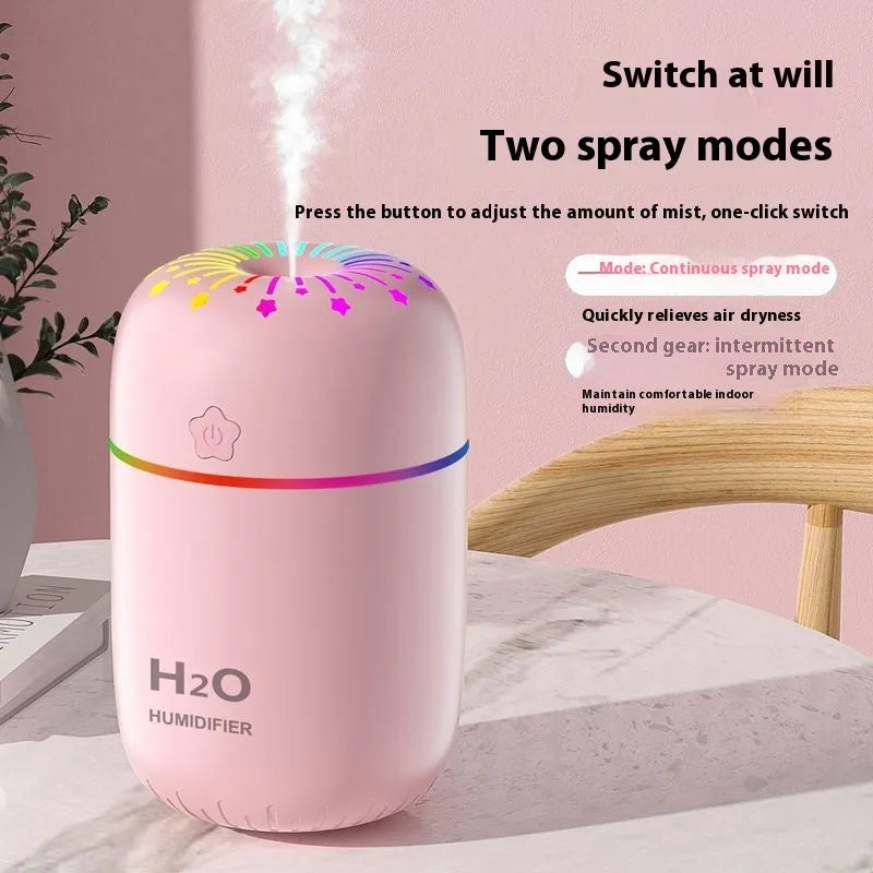 Small white Fireworks USB desktop humidifier with water tank on a wooden desk.