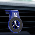 Black magnetic car phone holder clipped to a car air vent, showing a smartphone attached and the included fragrance slice.