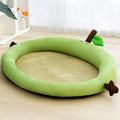 Green pet cooling mat with a raised fruit-shaped backrest, shown with a dog resting on it.