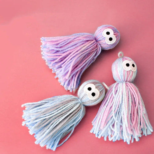 Blue grey wool ball cat toy with hanging loop next to a teaser stick.