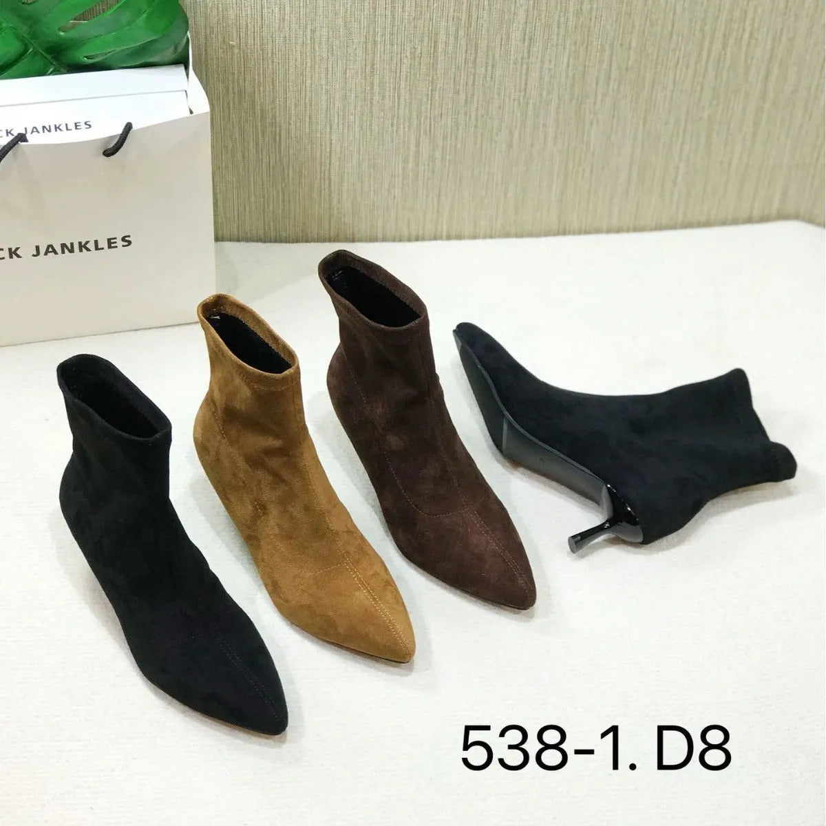 Black pointed toe ankle boots with a high stiletto heel on a woman's foot.