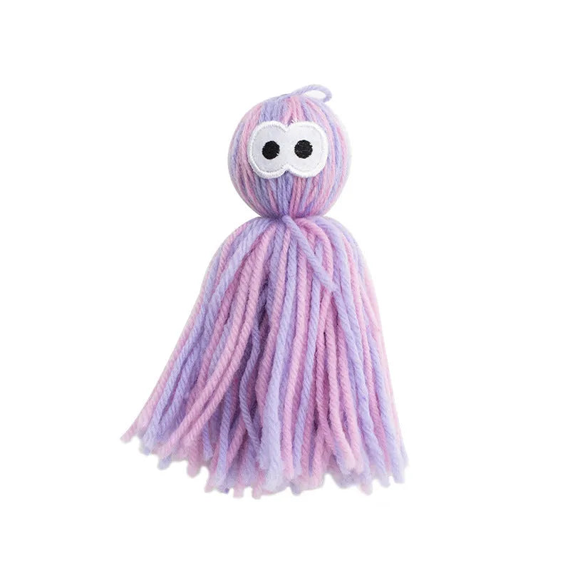 Blue grey wool ball cat toy with hanging loop next to a teaser stick.