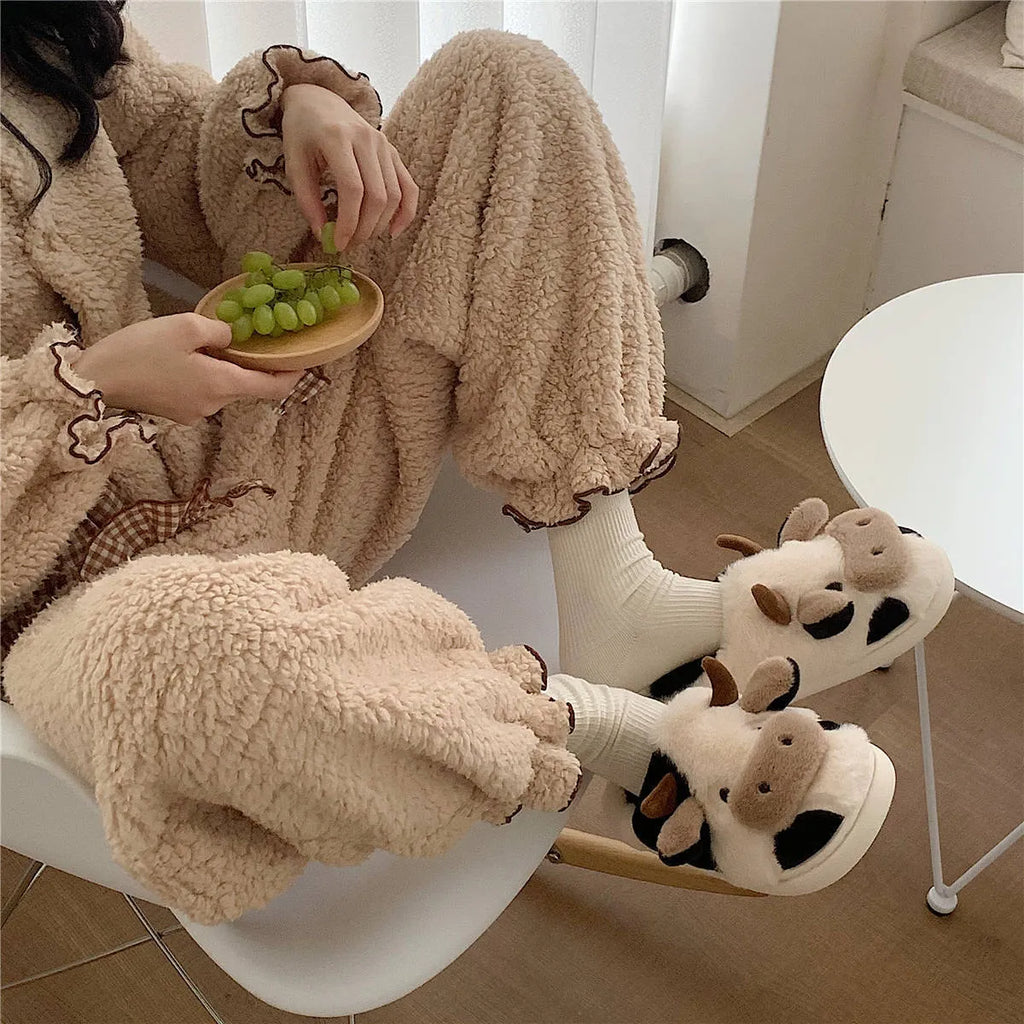 White cow plush slippers with non-slip textured soles shown from above