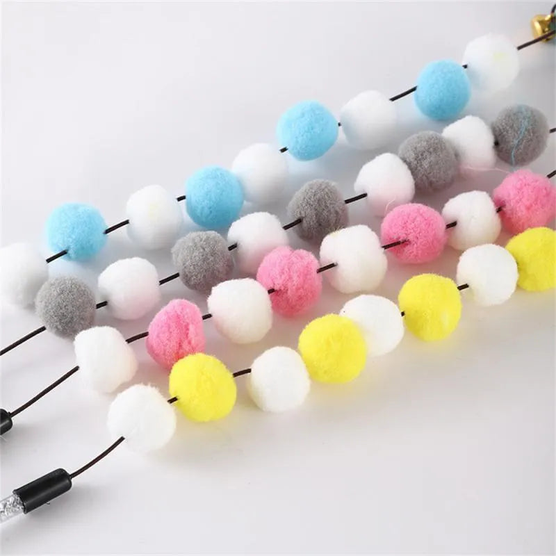 Grey and yellow cat teaser stick with a bell and a pompon feather, shown next to a blue and pink version.