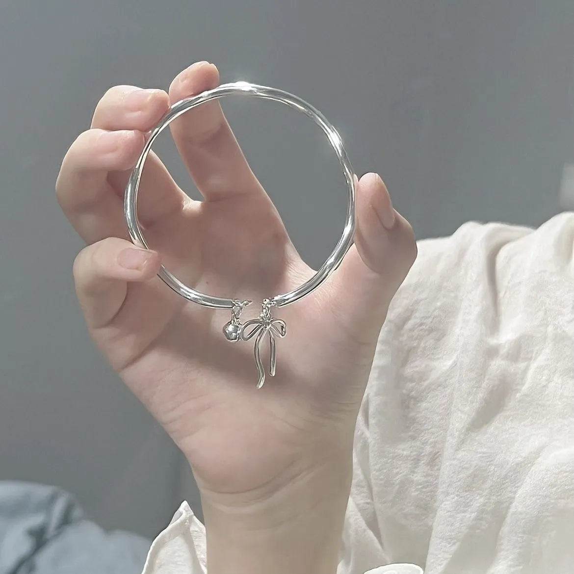 Silver adjustable bracelet with bow charm and sliding clasp mechanism