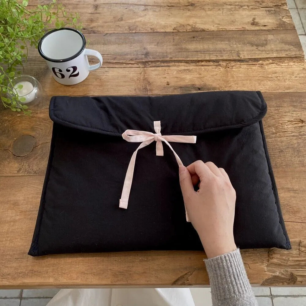 Women's black quilted computer bag with ballet bow detail showing striped nylon lining