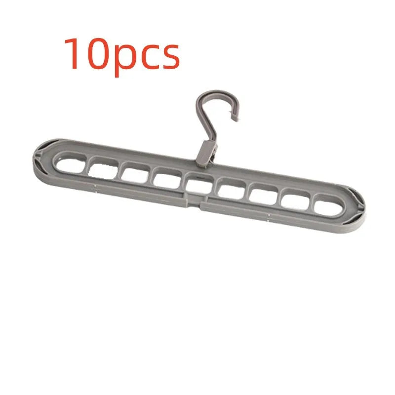 Green plastic multifunctional hanger with nine arms for folding trousers, shown hanging on a rail.