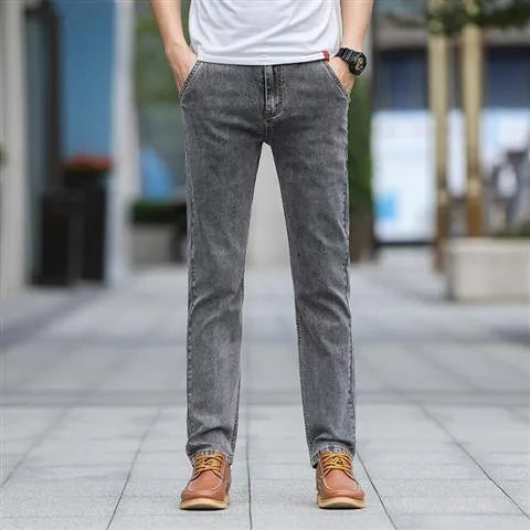 Man wearing smoky grey straight leg men's jeans with a low waist and zip fly.