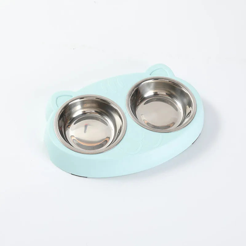 Blue plastic double bowl pet feeding tray for cats and dogs with non-slip rubber feet on a floor.