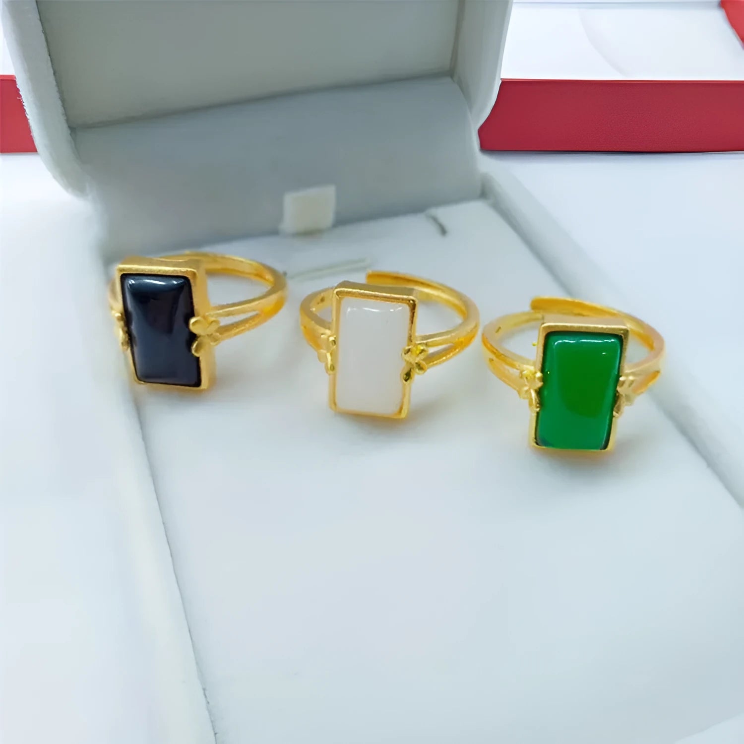 Adjustable brass gold-plated ring with a centre gemstone, shown in black, green, and white colour options.