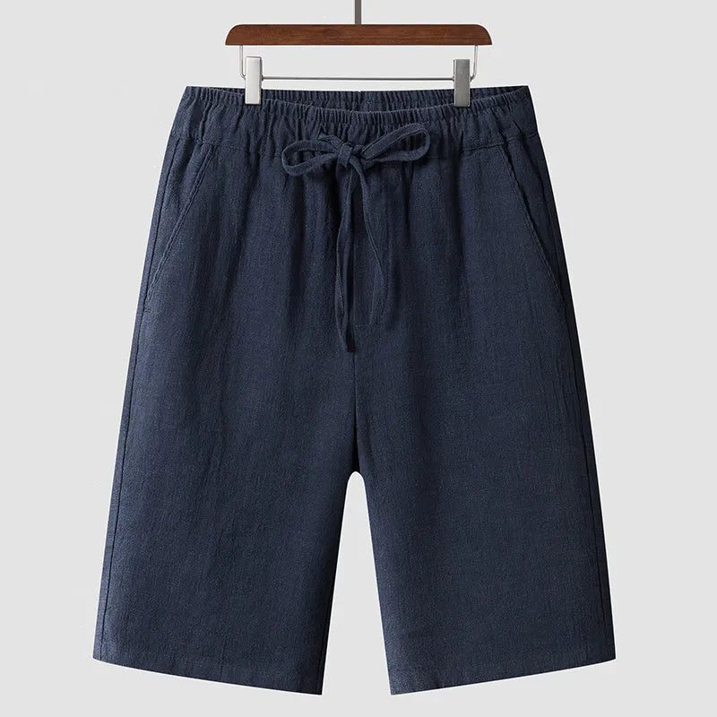 Men's beige linen casual shorts with loose cropped fit and elastic waistband laid flat