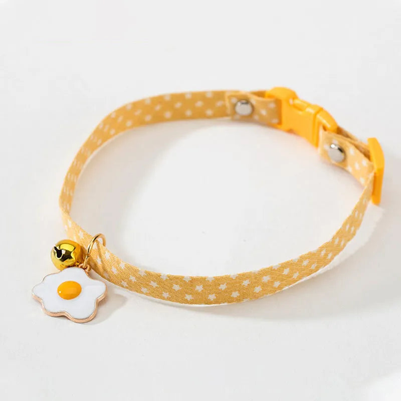 Green adjustable pet collar with a metal bell and a pink bow tie attached, shown on a small dog.
