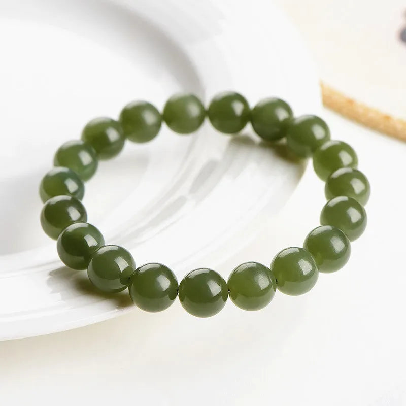 Polished Hetian jade ball bead bracelet in light and deep clear water colours on a wrist.