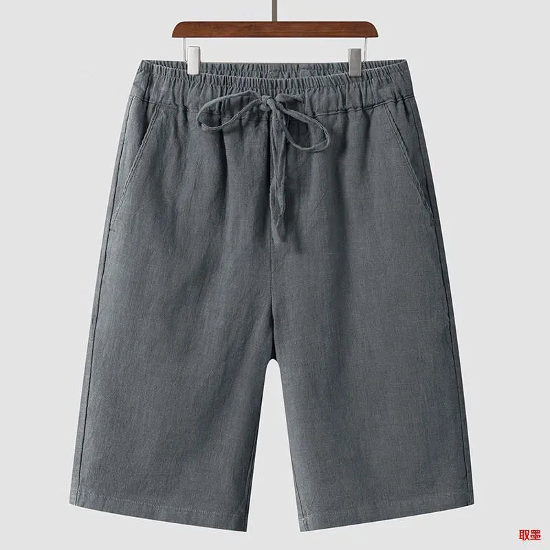 Men's beige linen casual shorts with loose cropped fit and elastic waistband laid flat