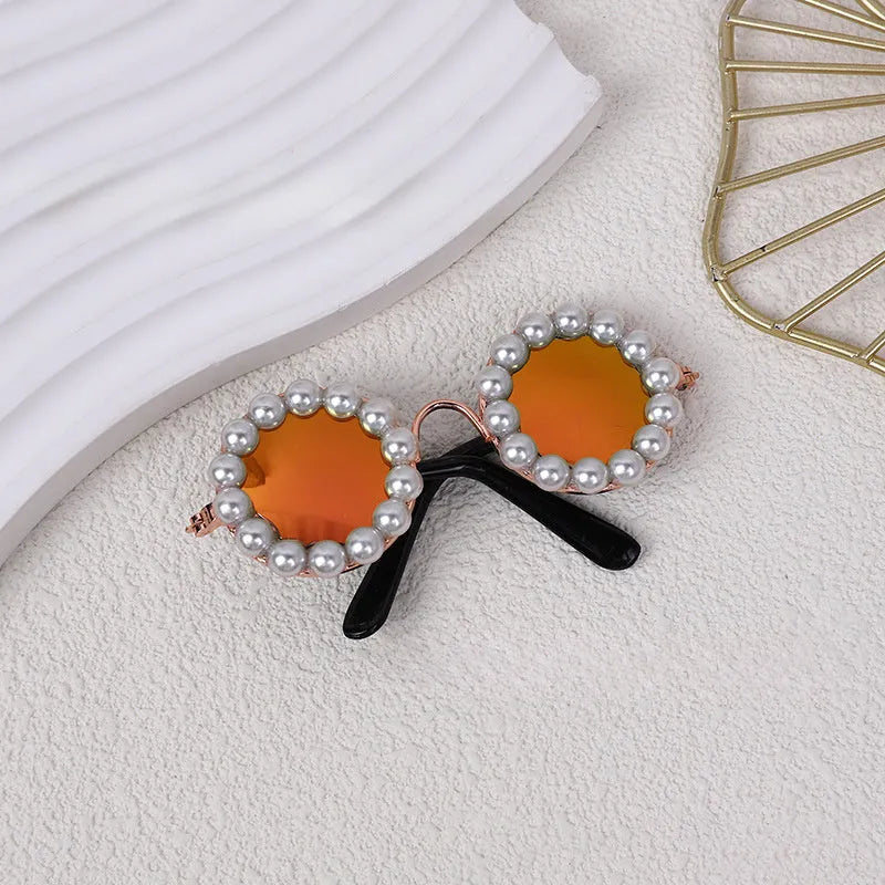 Pearl-rimmed round sunglasses for a cat or dog on a festive background.