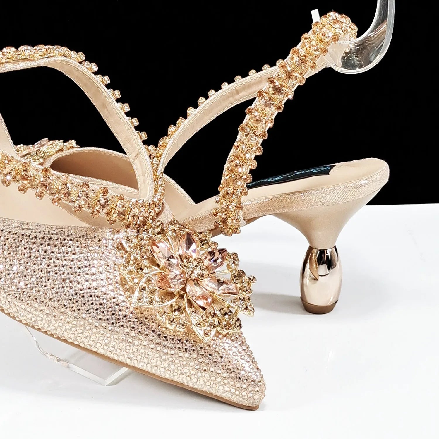 Women's black high heel sandals with ankle chain, floral rhinestone detail, and matching hard clutch bag