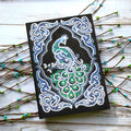 Black A5 diamond painting notebook with a peacock design cover, shown closed.