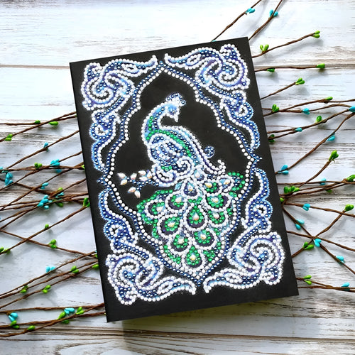 Black A5 diamond painting notebook with a peacock design cover, shown closed.