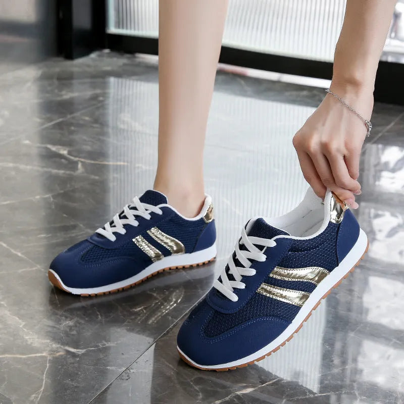 Blue women's lace-up tennis shoes with cross shoulder straps and a flat rubber sole.