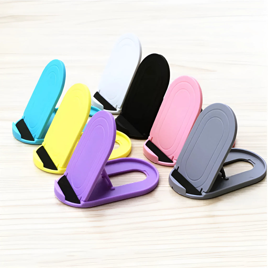 A lazy bracket style mobile phone stand made of plastic, shown in multiple colour options on a wooden desk.