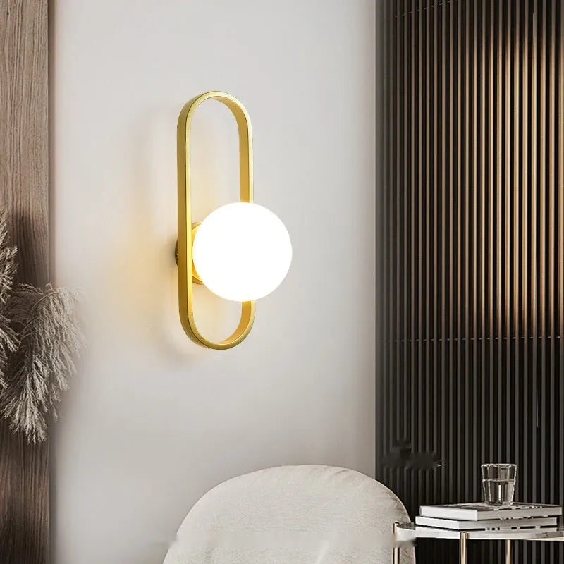 Minimalist modern wall lamp with glass shade and iron body in black finish, mounted on a wall.
