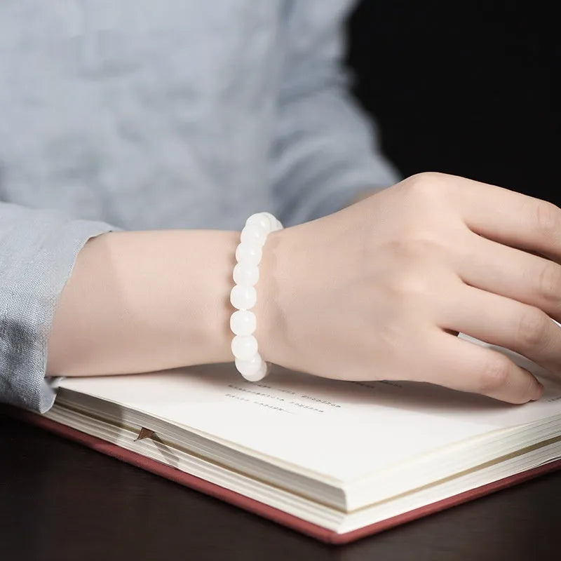 White Hetian jade barrel bead bracelet on a wrist, showing unisex casual style.