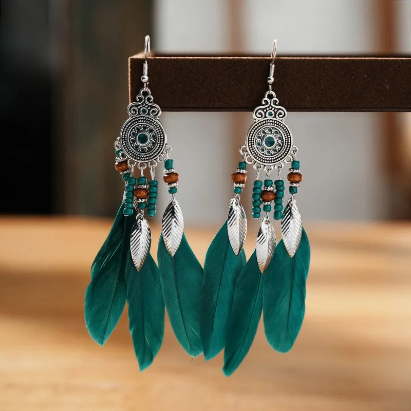 A pair of round drop leaf-shaped feather earrings in a chosen colour, showing Bohemian pattern details.
