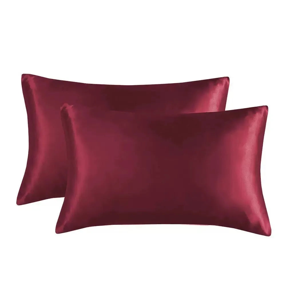 A pair of solid colour satin pillowcases in various colours and sizes on a bed.