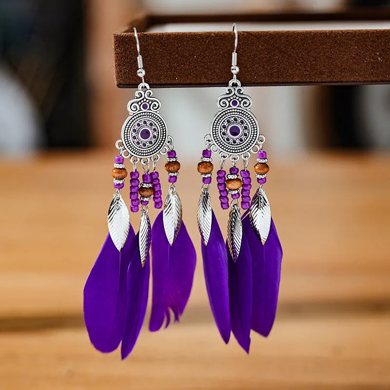 A pair of round drop leaf-shaped feather earrings in a chosen colour, showing Bohemian pattern details.