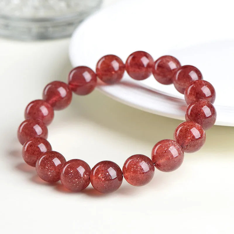 Natural strawberry quartz bracelet with geometry-shaped beads in starlight cherry red colour on a wrist.