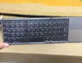 Black tri-fold folding Bluetooth keyboard with touchpad shown unfolded and folded