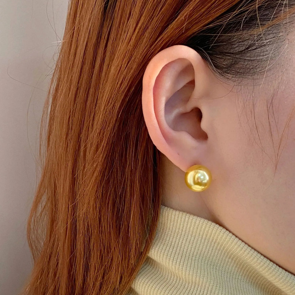 A pair of large geometric pearl stud earrings with a retro eight awn star motif on a silver setting.