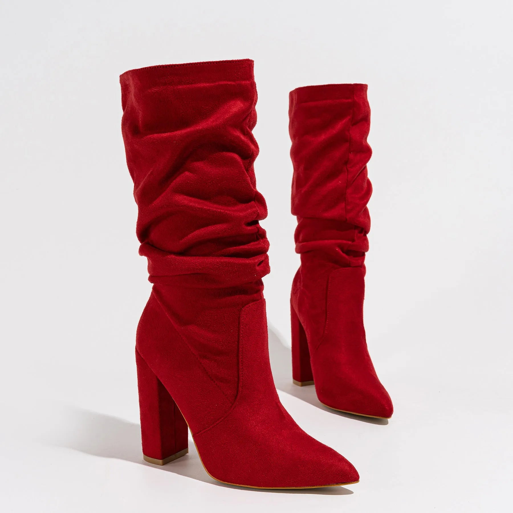 Women's black suede knee-high boots with a chunky high heel and pointed toe on a plain background.