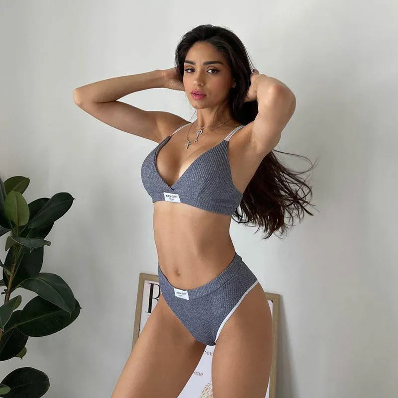 Women's black bikini set with white embroidery and contrast binding, showing sleeveless top and shorts.