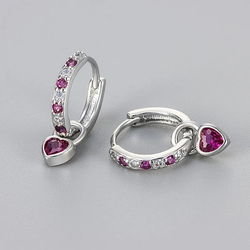 Women's fashion earrings with heart-shaped drops containing coloured gemstones in gold or white gold colour settings