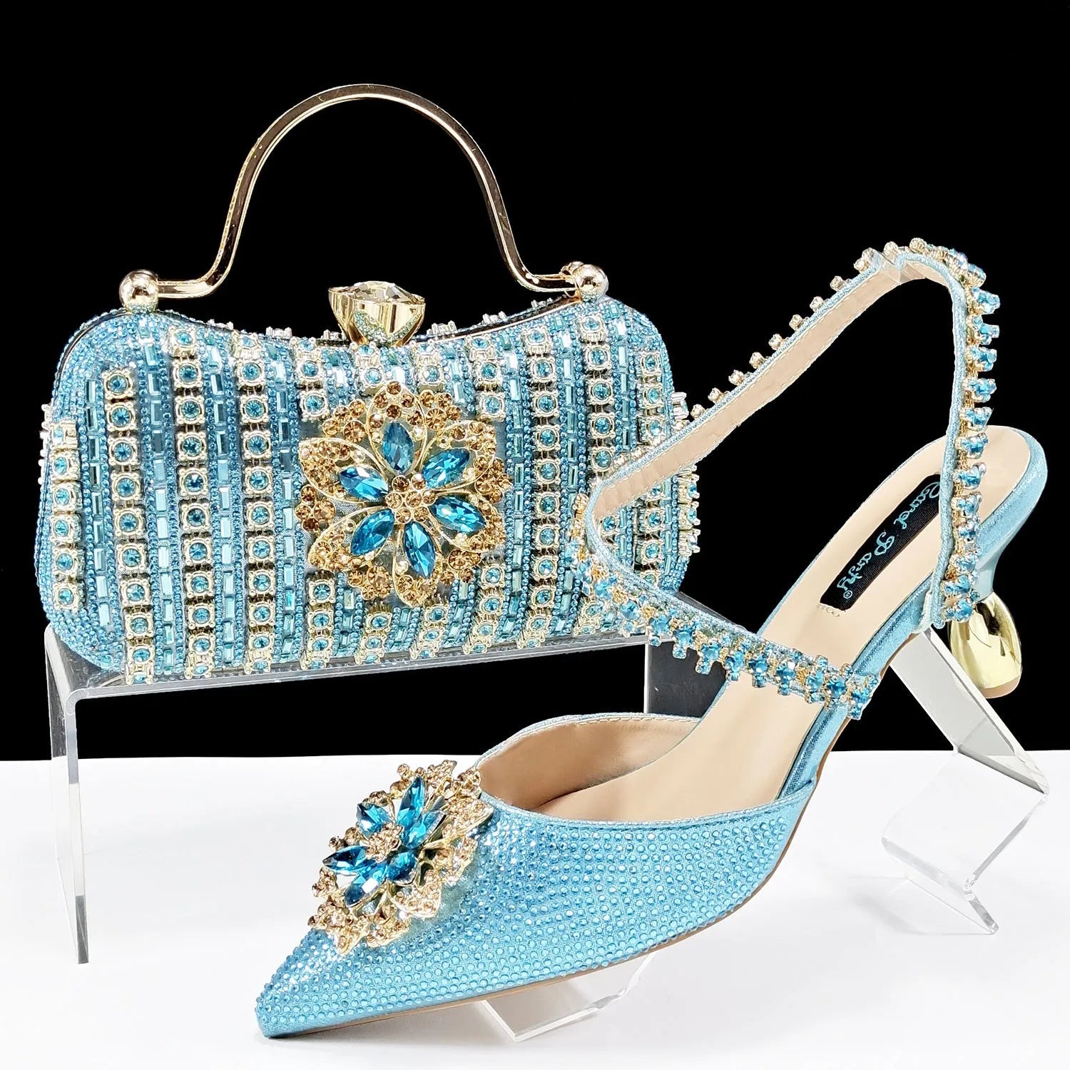 Women's black high heel sandals with ankle chain, floral rhinestone detail, and matching hard clutch bag