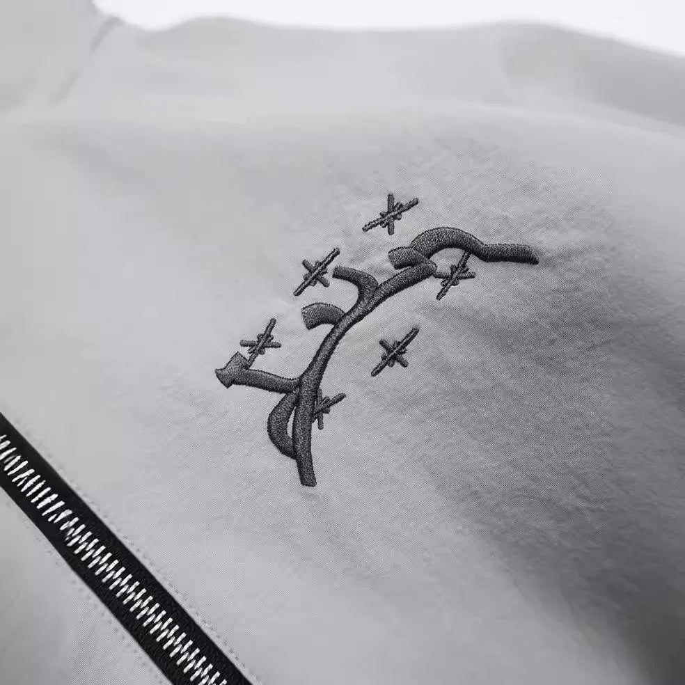 A grey men's hooded loose-fit sunscreen jacket on a hanger, showcasing its British-style design.
