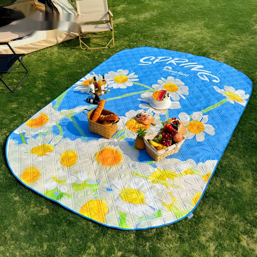Large green waterproof picnic mat laid out on grass for a group of people.