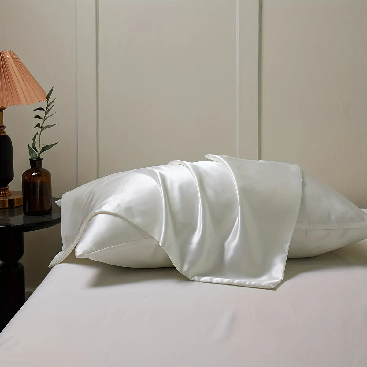 A pair of solid colour satin pillowcases in various colours and sizes on a bed.