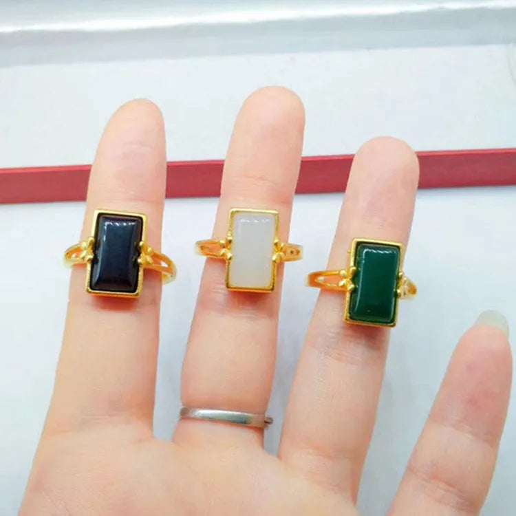 Adjustable brass gold-plated ring with a centre gemstone, shown in black, green, and white colour options.