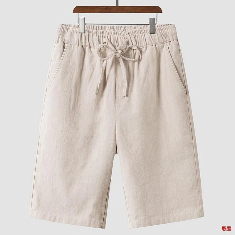 Men's beige linen casual shorts with loose cropped fit and elastic waistband laid flat